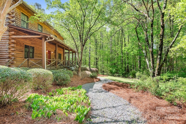 view of yard with a wooded view and covered porch