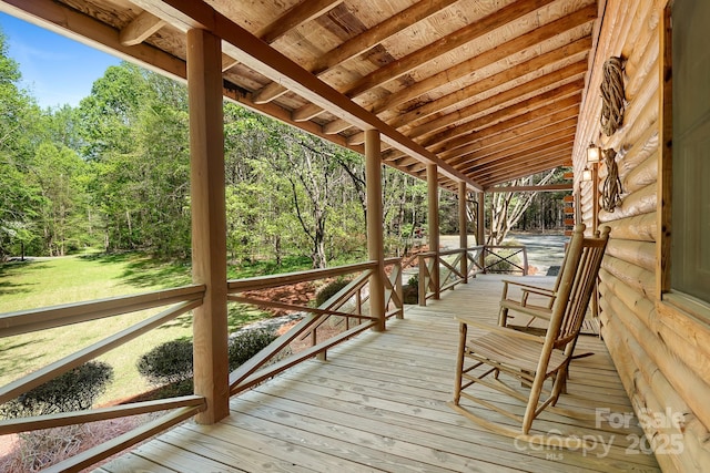 wooden deck with a view of trees and a lawn