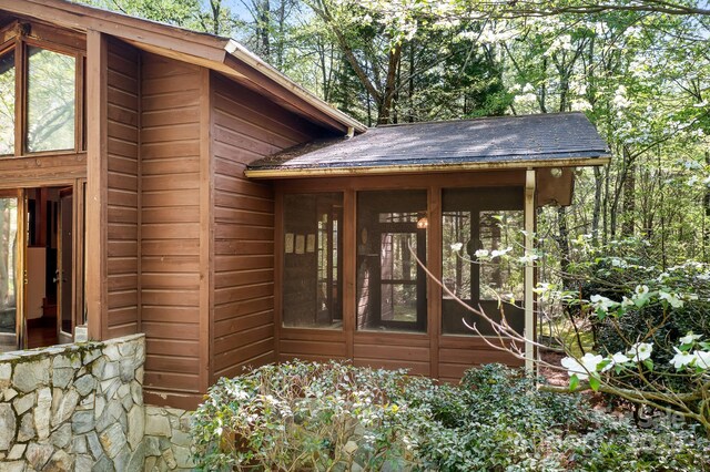 view of exterior entry with a shingled roof and stone siding