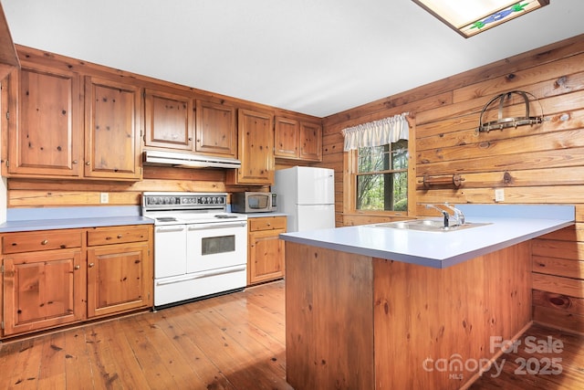 kitchen featuring a sink, light wood finished floors, white appliances, and under cabinet range hood
