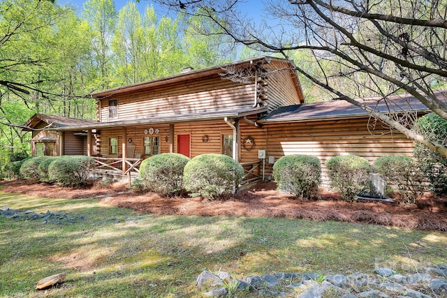 log-style house featuring log siding, covered porch, and a front lawn