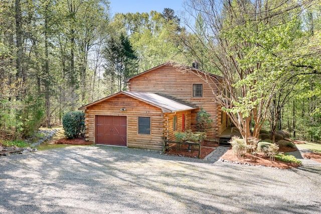 log cabin with driveway, log exterior, metal roof, and a garage