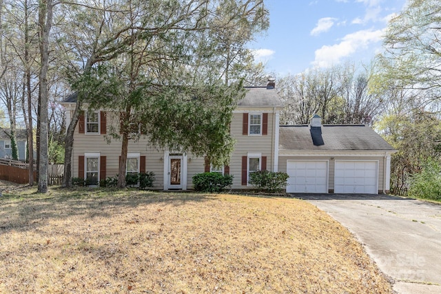 colonial home with driveway, an attached garage, and a chimney