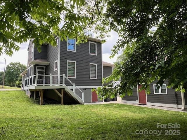 back of house featuring stairway, a lawn, and a deck