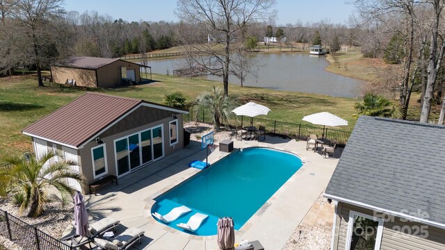 view of swimming pool with an outdoor structure, a water view, a yard, and a patio