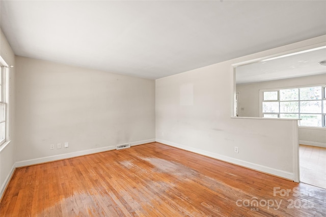 spare room with visible vents, baseboards, and wood-type flooring