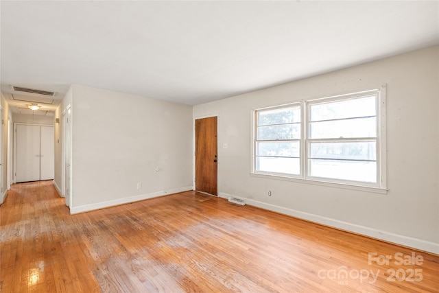 spare room featuring visible vents, light wood finished floors, and baseboards