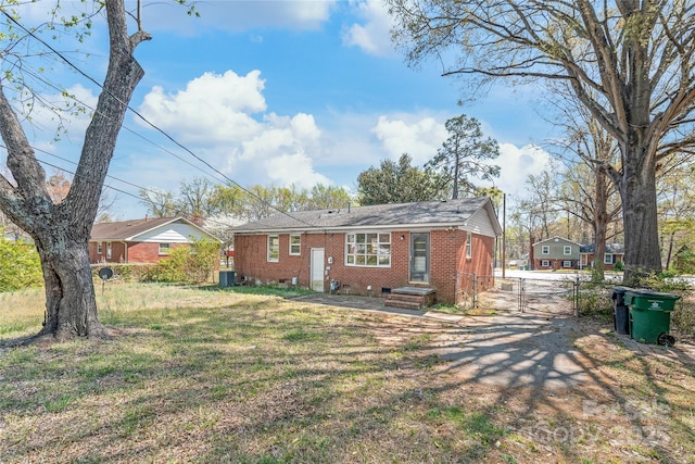exterior space with a gate, a yard, crawl space, central AC, and brick siding