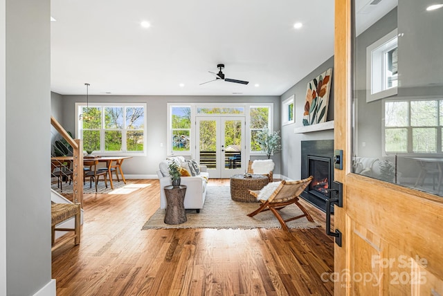 living room with a wealth of natural light, wood finished floors, a ceiling fan, and baseboards