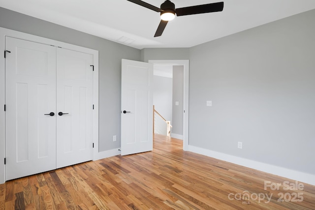 unfurnished bedroom featuring baseboards, ceiling fan, a closet, and light wood-style flooring
