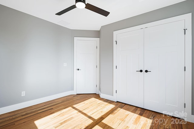 unfurnished bedroom with a closet, wood finished floors, and baseboards