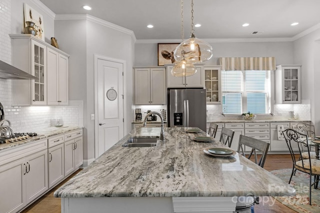 kitchen featuring a sink, light stone countertops, an island with sink, and appliances with stainless steel finishes