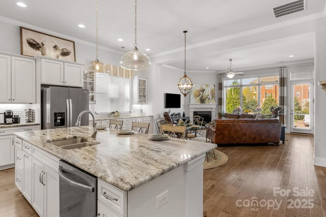 kitchen featuring visible vents, a fireplace, stainless steel appliances, a ceiling fan, and a sink
