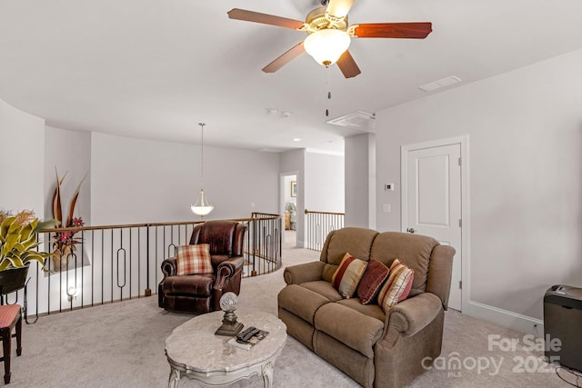 living room with attic access, light colored carpet, visible vents, and a ceiling fan