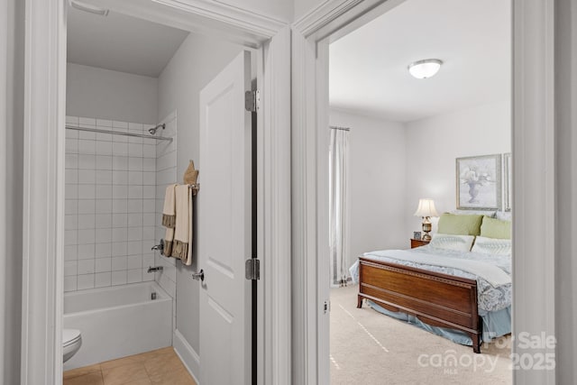 ensuite bathroom featuring toilet, ensuite bathroom, tub / shower combination, and tile patterned flooring