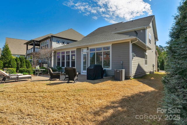 back of house with a lawn, central air condition unit, roof with shingles, and a patio