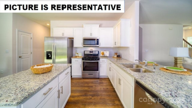 kitchen featuring appliances with stainless steel finishes, white cabinets, light stone countertops, decorative backsplash, and a sink