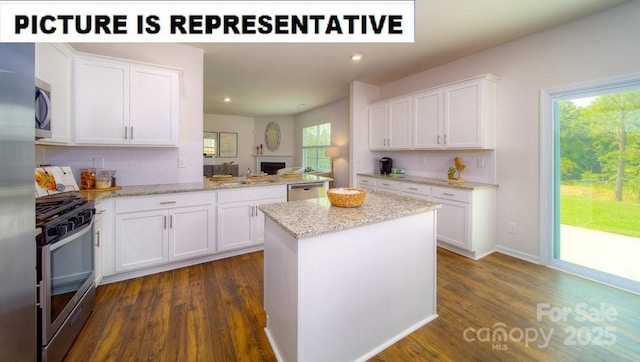 kitchen with white cabinets, dark wood-style flooring, a center island, and appliances with stainless steel finishes