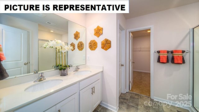 full bathroom featuring a walk in closet, double vanity, a sink, and visible vents