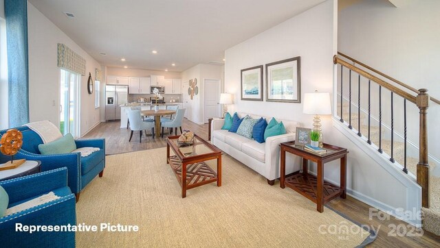 living area with stairway, baseboards, recessed lighting, and light wood-type flooring
