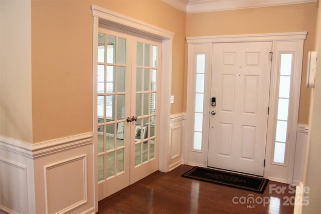 foyer entrance featuring french doors, a wainscoted wall, a decorative wall, ornamental molding, and dark wood-style floors