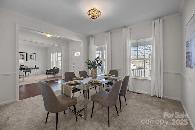dining space with baseboards, visible vents, crown molding, and light colored carpet