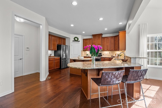 kitchen with a sink, appliances with stainless steel finishes, baseboards, dark wood-style flooring, and a peninsula