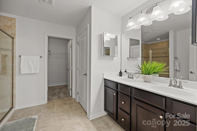 bathroom with a spacious closet, a stall shower, double vanity, and a sink