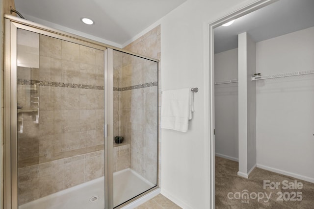 bathroom with baseboards, a spacious closet, a stall shower, and recessed lighting