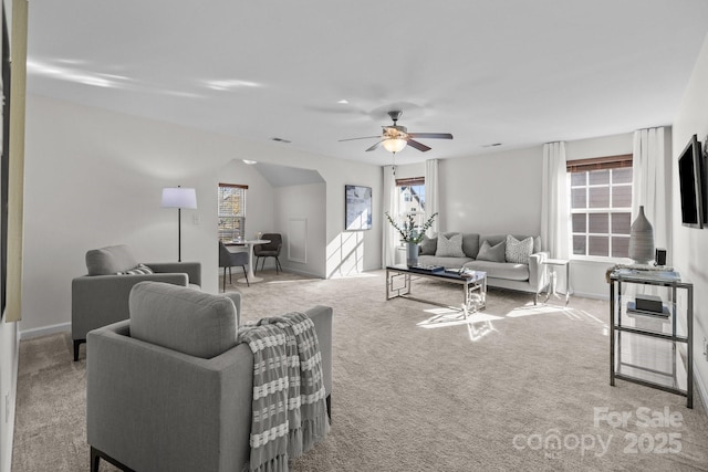 carpeted living room with ceiling fan, arched walkways, and baseboards