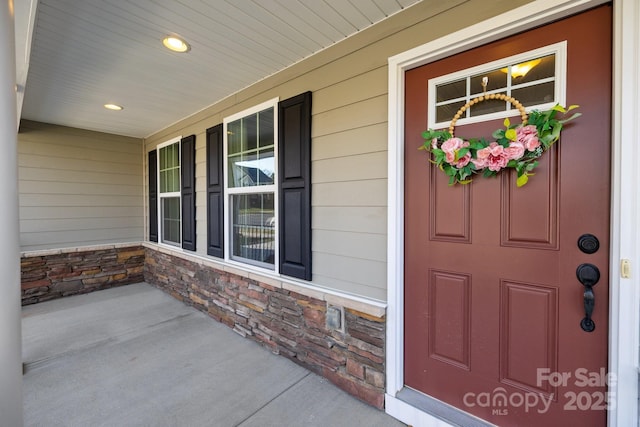 view of exterior entry with a porch and stone siding