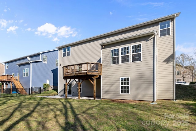 rear view of house with a lawn, fence, a wooden deck, and stairs