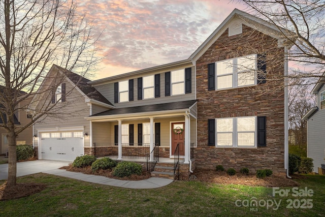 traditional home with a front lawn, a garage, covered porch, stone siding, and concrete driveway