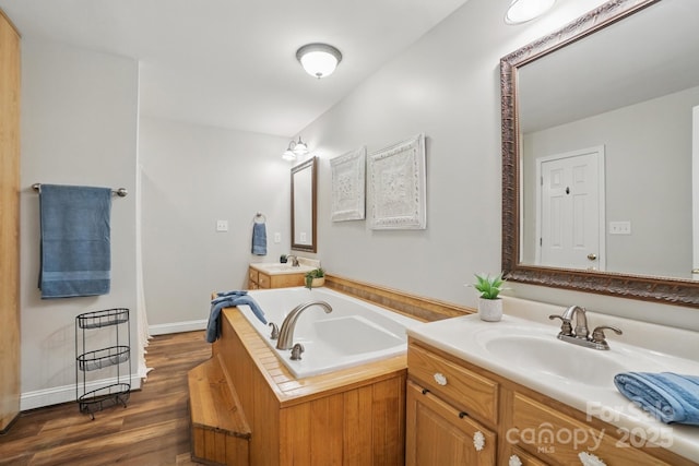 9711 Pine Tree Rd, Norwood, NC 28128 - full bathroom featuring a garden tub, two vanities, wood finished floors, and a sink