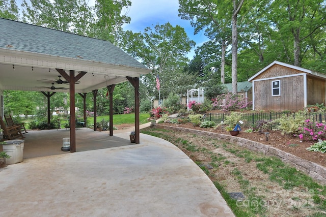 view of yard featuring an outbuilding, a ceiling fan, fence, and a patio area