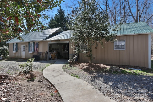 ranch-style house featuring metal roof, gravel driveway, and a garage