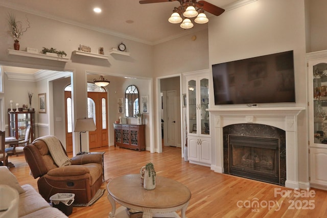 living room featuring ornamental molding, ceiling fan, light wood-style floors, and a fireplace