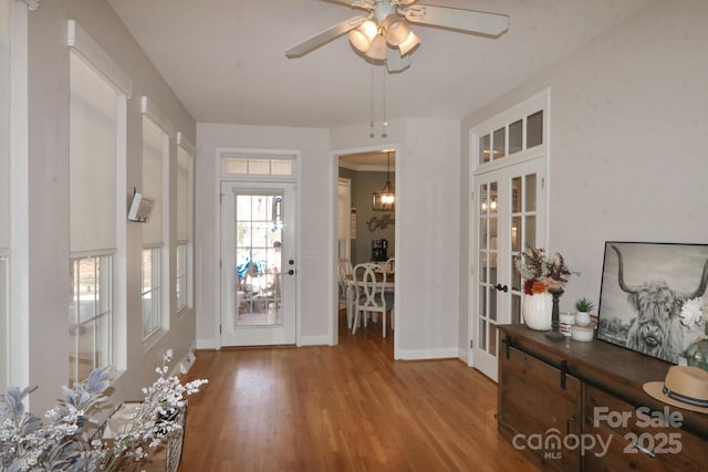 foyer entrance featuring baseboards, wood finished floors, a ceiling fan, and french doors