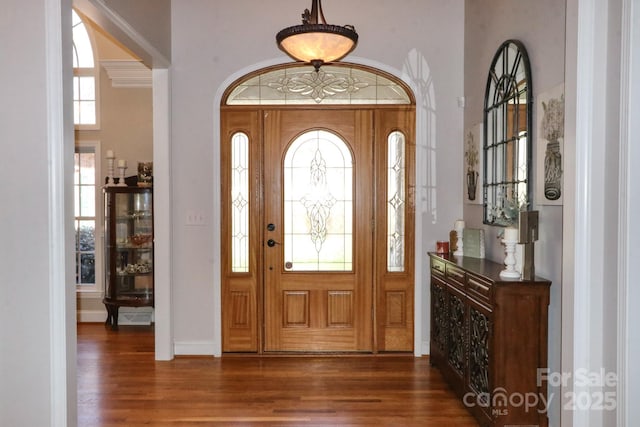 foyer with a towering ceiling, dark wood finished floors, and baseboards