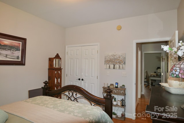 bedroom featuring baseboards, wood finished floors, and a closet