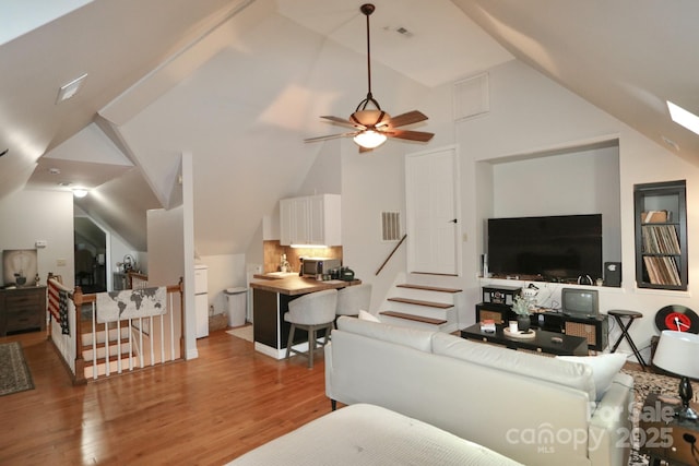 living room featuring wood finished floors, ceiling fan, visible vents, and vaulted ceiling