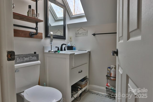 bathroom with toilet, vanity, and a skylight