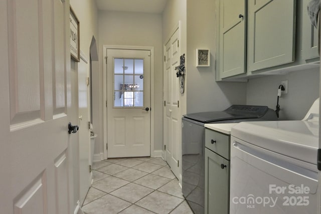 clothes washing area with light tile patterned floors, washer and dryer, and cabinet space