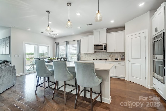 4337 Duplin Dr, Charlotte, NC 28214 - kitchen with decorative backsplash, visible vents, stainless steel appliances, dark wood-type flooring, and an island with sink