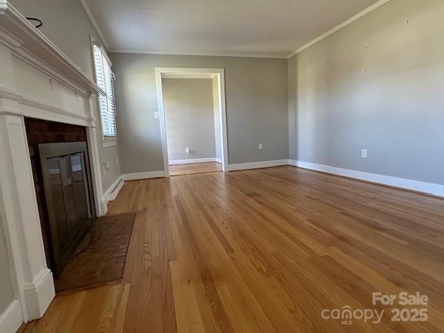 unfurnished living room featuring baseboards, light wood-style floors, and crown molding