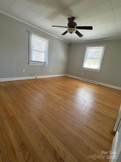 unfurnished room featuring baseboards, ornamental molding, and light wood-style flooring