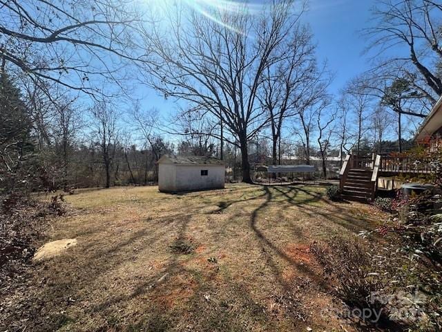 view of yard featuring a storage unit, stairs, an outbuilding, and a deck