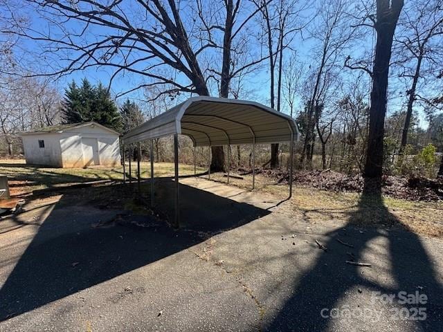 view of yard featuring a detached carport and aphalt driveway