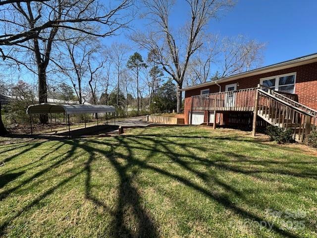 view of yard featuring a detached carport, a wooden deck, and stairway