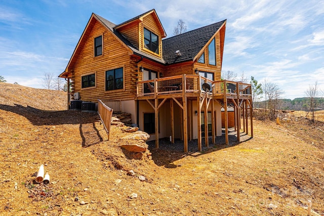 rear view of property with a shingled roof, central AC, a wooden deck, and log siding